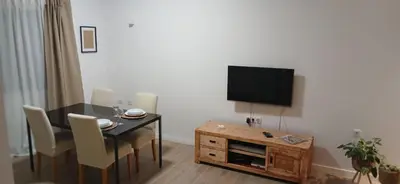 a living room with a table and a flat screen tv at Avenida Dr Baltazar Lopes da Silva 33A in Mindelo