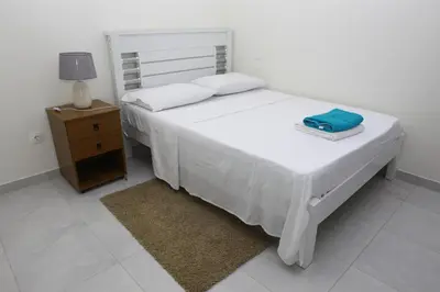 a white bedroom with a bed and a night stand at Sonho Appartement in Praia