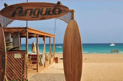 a wooden surfboard on a beach with the ocean at Good value low cost apartment second beach line in Santa Maria
