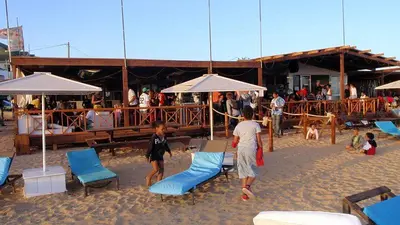 a group of people on a beach with chairs and umbrellas at Good value low cost apartment second beach line in Santa Maria