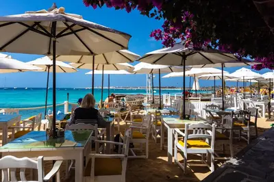 a beach cafe with white chairs and tables and umbrellas at Hotel Odjo d'água in Santa Maria