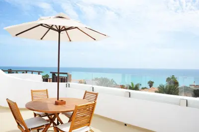 a table with an umbrella on a balcony with the ocean at Hotel Odjo d'água in Santa Maria