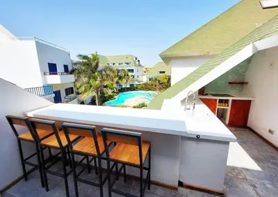 a balcony with two chairs and a table and a pool at Penthouse with rooftopbar, Fiber WiFi, next to the beach! in Santa Maria