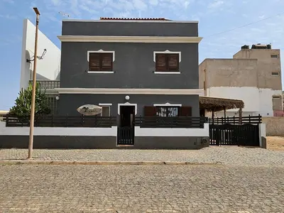 a gray house with a black door in a street at Blue Eagle Guesthouse - Casa de hospedes in Santa Maria