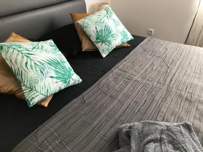 a bed with three pillows on it with a table at Blue Eagle Guesthouse - Casa de hospedes in Santa Maria