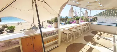a bar with a view of the beach and an umbrella at Beach penthouse with rooftopbar and Fiber WiFi, spectacular 180 degrees ocean view in Santa Maria