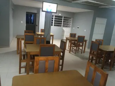a dining room with tables and chairs and a television at Pensao Motel Sodade in São Filipe