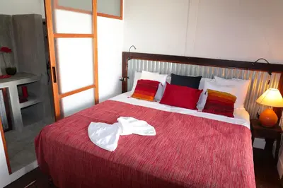 a bedroom with a large red bed with red pillows at Casa Colonial Koenig in São Filipe