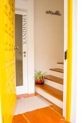 a hallway with a yellow door and stairs at Apartamento Xandinha Amwilla Guesthouse in Mindelo