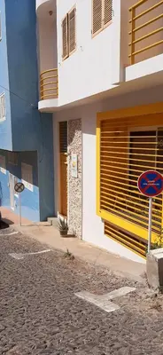 a building with a sign on the side of a street at Apartamento Xandinha Amwilla Guesthouse in Mindelo