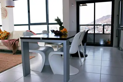 a dining room with a table and white chairs at Kasa Imbondeiro in Mindelo