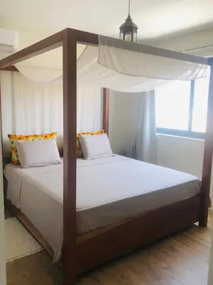 a bedroom with a canopy bed with white sheets at Kasa Imbondeiro in Mindelo