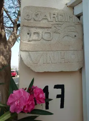a sign with flowers on the side of a building at O Jardim do Vinho, AC in Praia