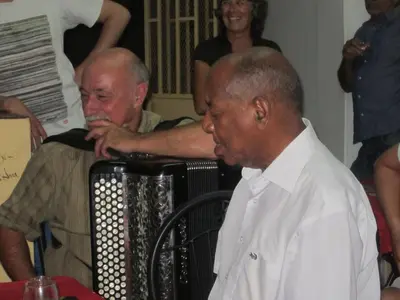 two men are standing next to a accordion at O Jardim do Vinho, AC in Praia