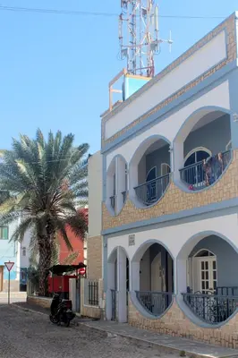 a white building with a palm tree in front of it at Residence A Paz in Boa Ventura