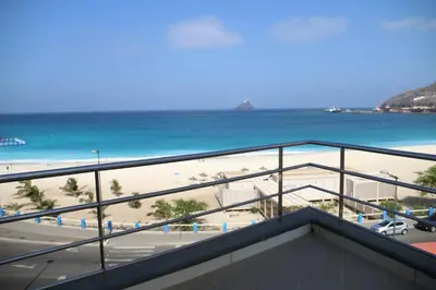 a view of a beach and the ocean from a balcony at Complexo Multiuso Copacabana in Mindelo
