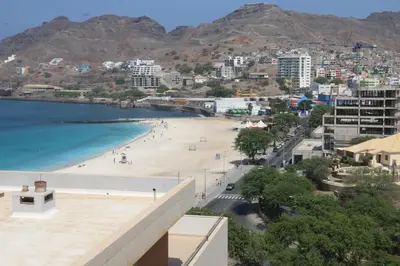a view of a beach with mountains in the background at Complexo Multiuso Copacabana in Mindelo