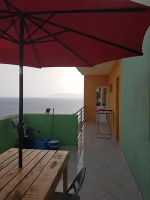 a patio with a wooden table and an umbrella at chez albino guest house in São Filipe