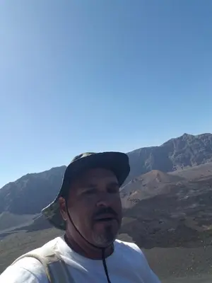 a man wearing a hat standing in the mountains at chez albino guest house in São Filipe