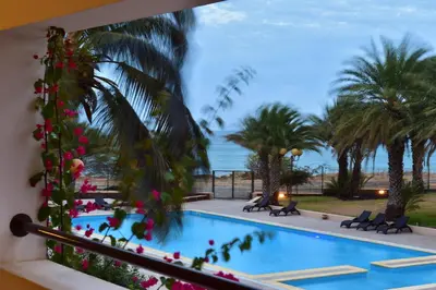 a pool with palm trees and the ocean in the background at Pestana Tropico Ocean & City Hotel in Praia