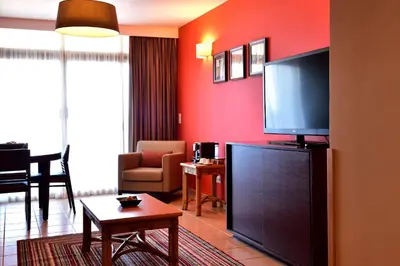 a living room with a large flat screen tv at Pestana Tropico Ocean & City Hotel in Praia