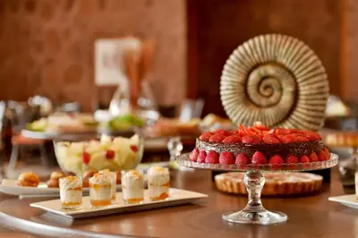 a table topped with desserts and a plate of food at Pestana Tropico Ocean & City Hotel in Praia