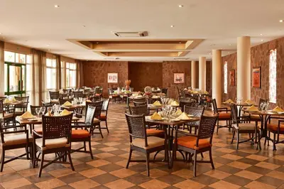 a restaurant with tables and chairs in a room at Pestana Tropico Ocean & City Hotel in Praia