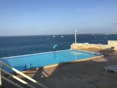 a person is in a swimming pool near the ocean at Residenz Stella Maris Apartment Strela in Vila do Maio