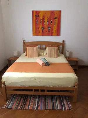 a bedroom with a bed with a painting on the wall at Charming 2BR with Refreshing Ocean View in Praia