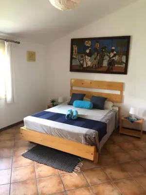 a bedroom with a wooden bed with blue pillows at XXL Apt w/ Surprising Gorgeous Ocean View in Praia