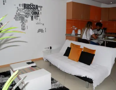 a living room with a couch and people in the kitchen at Domingas in Praia