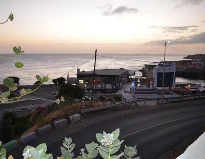 an empty road next to the ocean at sunset at Domingas in Praia