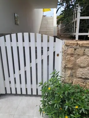 a white fence in front of a house with a plant at Vivenda Ronnie in Beirona