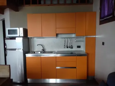 a kitchen with orange cabinets and a sink and a refrigerator at Sal&Love apt in Porto Antigo in Santa Maria
