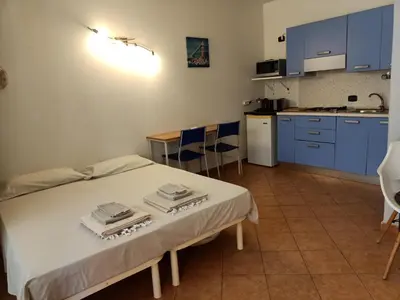 a room with a bed and a kitchen with blue cabinets at Sal&Love apt in Porto Antigo in Santa Maria