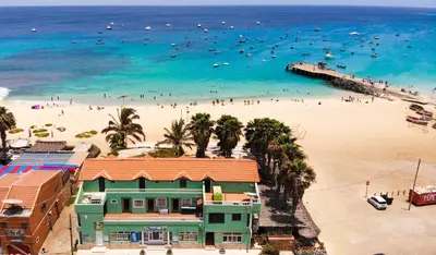 a beach with a green house and people in the water at Mister Barracuda in Santa Maria