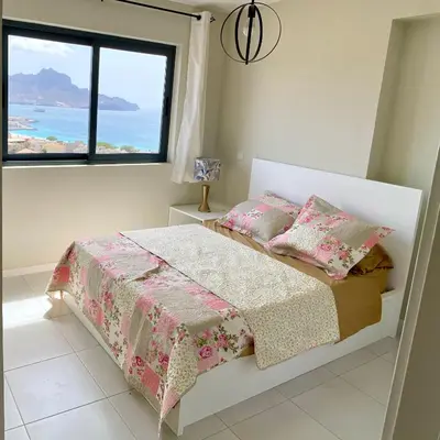 a bedroom with a bed with a view of the ocean at Ocean View Stay in Mindelo
