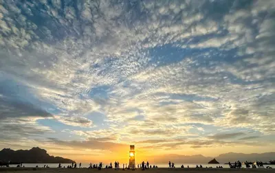 a group of people standing on a beach with a lighthouse at Ocean View Stay in Mindelo