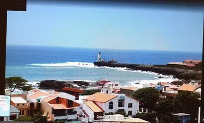 a lighthouse on a beach with houses and a lighthouse at Secularis Capital in Praia