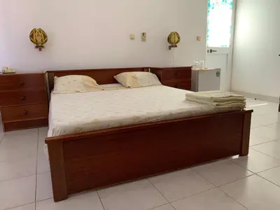 a large bed in a bedroom with a wooden frame at Residencial Pôr do Sol in Porto Novo