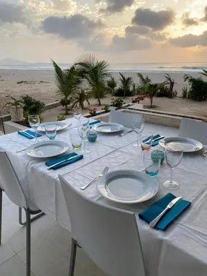 a table with plates and wine glasses on the beach at Villa Alfredo Marchetti Nº13 A Suites on the Beach, Praia de Chaves, Boa Vista in Cabeçadas