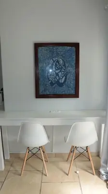 two white chairs sitting next to a table with a picture at Apartamento Moradias Djadsal C01 próximo à Praia de Santa Maria in Espargos