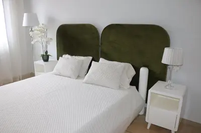 a bedroom with a white bed with a green headboard at Apartamento Moradias Djadsal C01 próximo à Praia de Santa Maria in Espargos