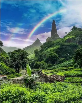 a rainbow in the sky over a green mountain at Pousada do Ceu in Paul