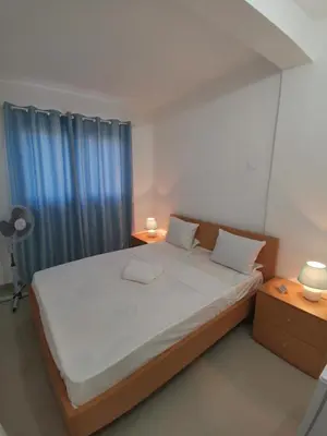 a bedroom with a large bed with blue curtains at Plateau Bedroom & Chambre - Praia Center 1 in Praia