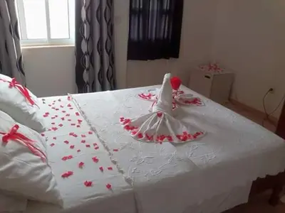 a white bed with red flowers on it at Hotel Avenida in Assomada
