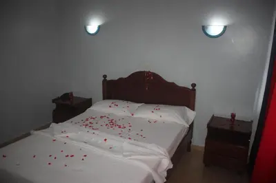 a bedroom with a bed with red rose petals on it at Hotel Avenida in Assomada