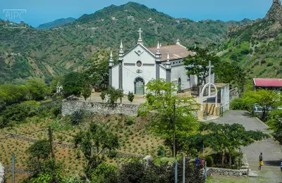 a church on the side of a hill with mountains at Hotel Avenida in Assomada