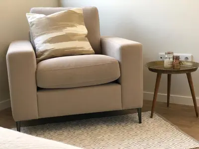 a chair with a pillow and a side table at Harmony apartment in Mindelo São Vicente in Mindelo