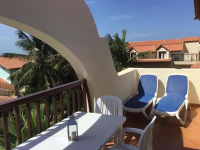 a balcony with two blue chairs and a table at Apt71 Porto Antigo 2 in Santa Maria